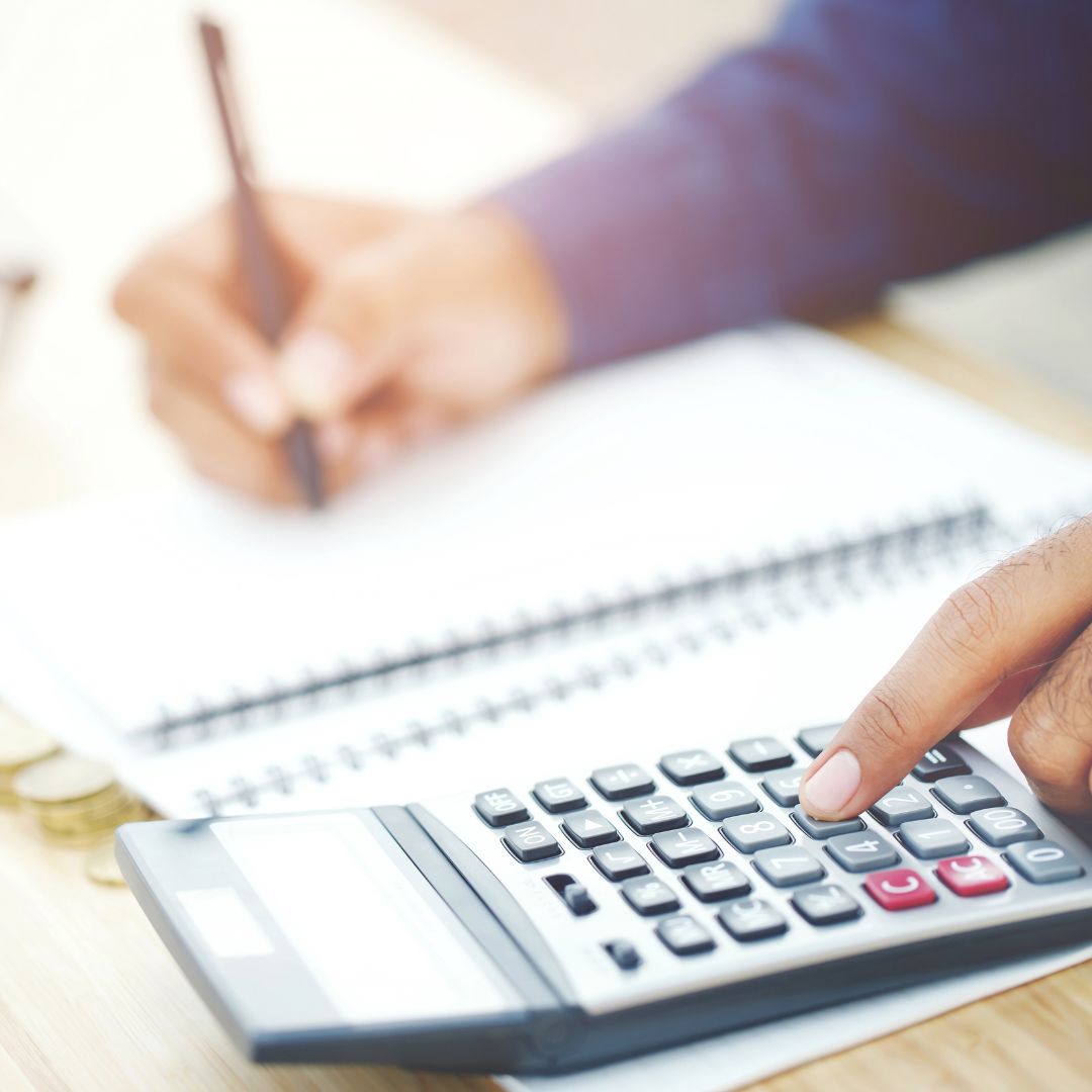 a person using a calculator and writing information down