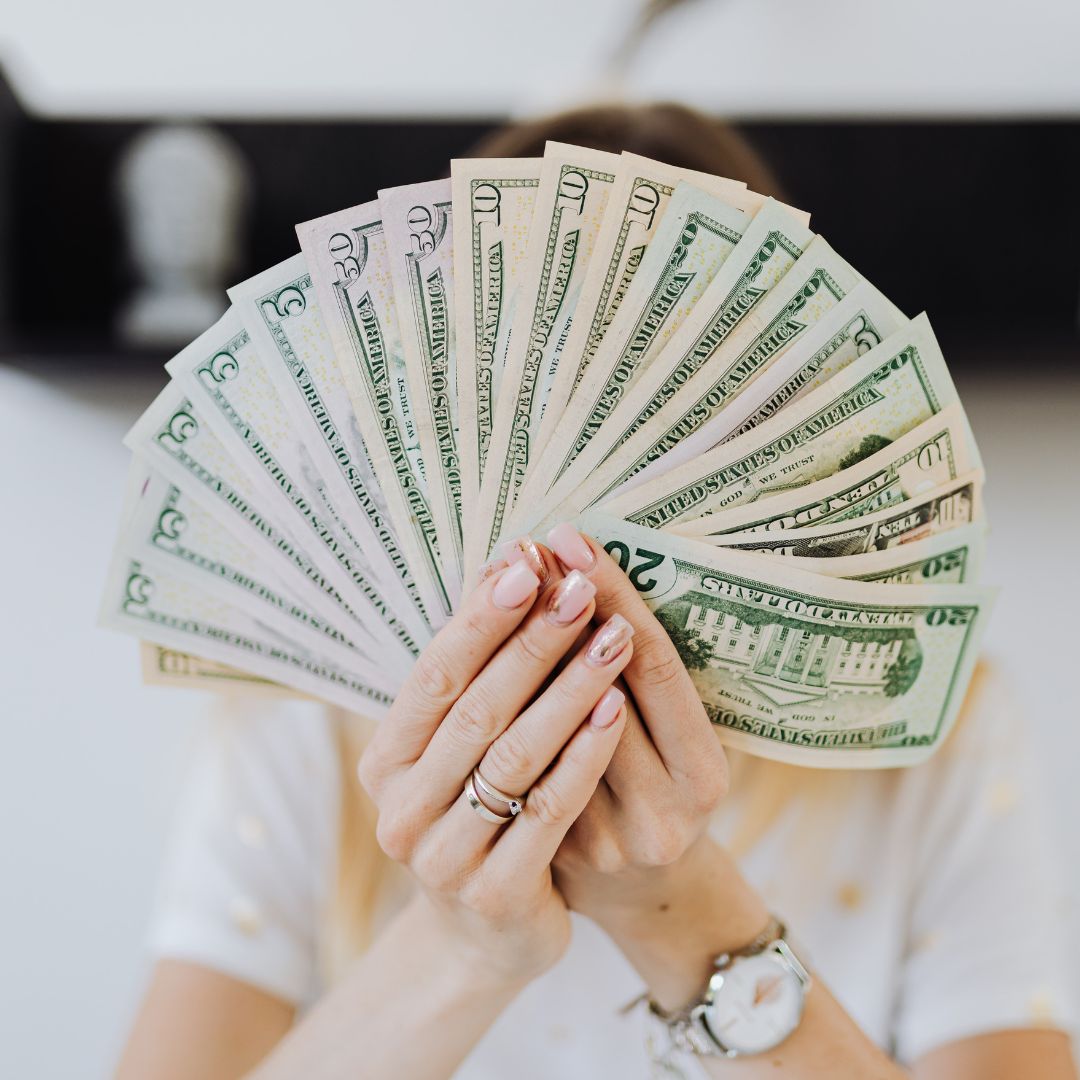 a person with a fan of twenty dollar bills